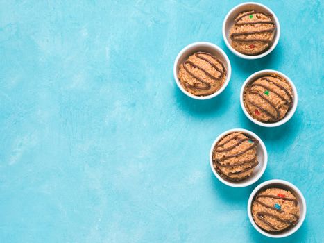 Safe-to-eat raw monster cookie dough in small portion bowl on blue background. Ideas and recipes for kids and toddlers meal. Top view or flat-lay. Copy space for text.