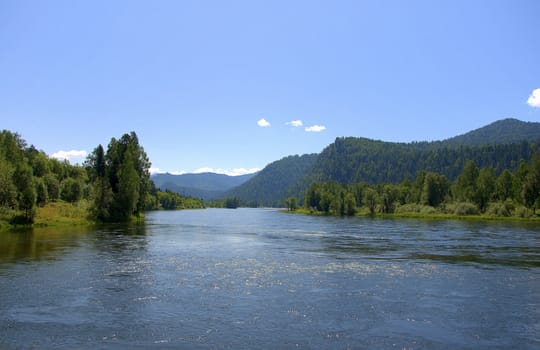 A calm river flowing through a valley at the foot of the mountains. Altai, Siberia, Russia.