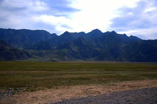 Fertile pasture at the foot of low rocky mountains. Altai, Siberia, Russia.