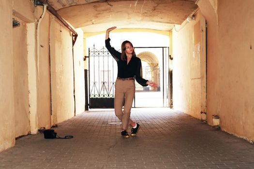 Beauty girl dancing in the arch of the house against sunlight