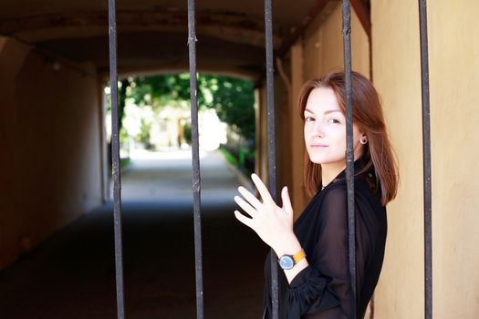 Beauty young woman in front of the old lattice gate in house arch
