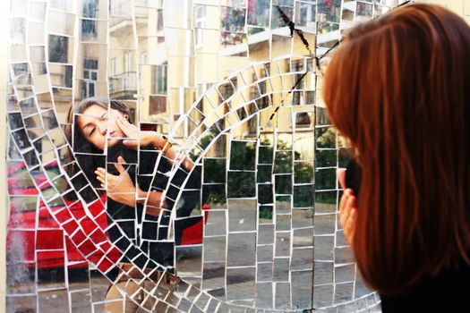 The beauty girl's reflection in the mirror on building wall