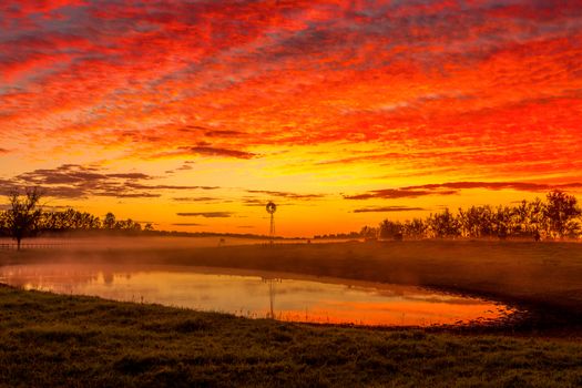 Blazing red sunrise sky over rural farmland landscape Australia