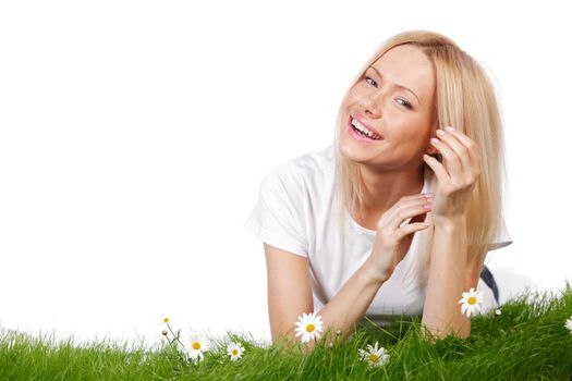 Beautiful young blonde woman lying on grass with chamomile flowers, isolated on white background