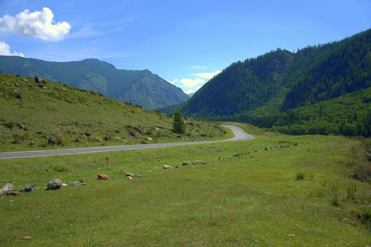 Asphalt road running through a mountain field valley. Chuysky tract, Altai, Siberia, Russia.