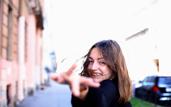 The beauty young woman with waving hair runs through the city