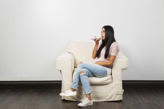 Young woman, sitting on a white couch, talking on her phone