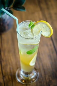 Mojito cocktail with lime and mint in high glass on wooden table.