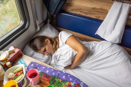 A young girl sleeps on the bottom bunk in a train