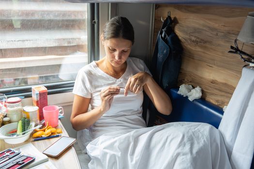 The girl cuts her nails in the reserved seat of the train