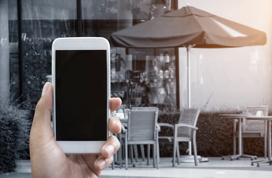 Man's hand shows mobile smartphone in vertical position and blurred background - smartphone mockup template