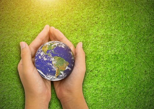 Earth planet in asian Children hand on green grass background. - Elements of this image furnished by NASA