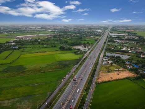 Aerial view of rural tree covered countryside with highway of road passing through farmland fields in Thailand, Viewed from above, Aerial view. Top view photo from Drone.