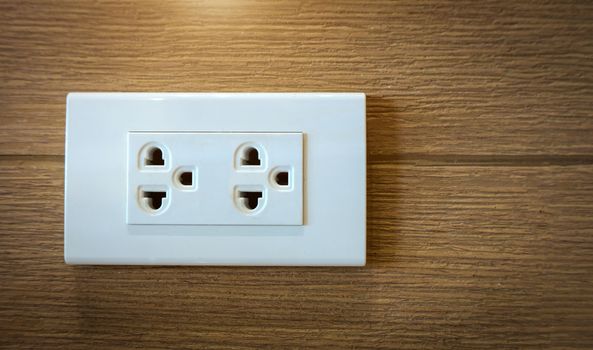 Electrical plug socket on wooden wall.