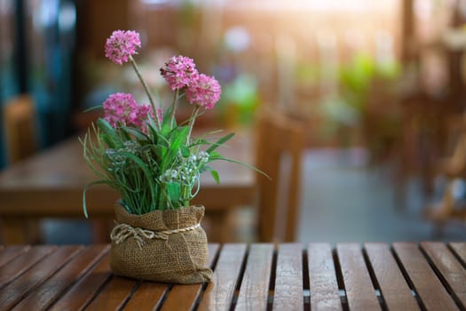 Closeup many pink flower in vase on wooden table and sunlight.