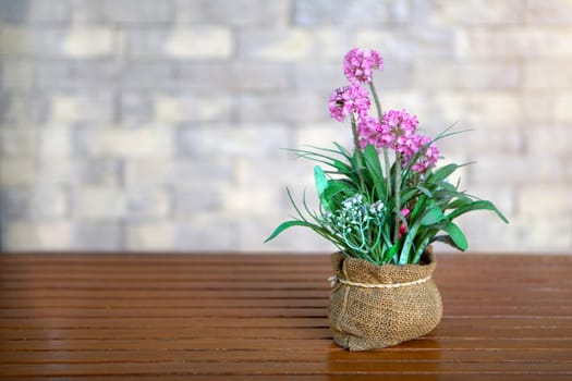 Closeup many pink flower in vase on wooden table and sunlight.