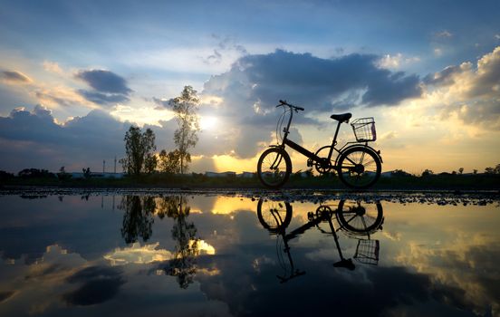 Reflection of Silhouette bicycle park on the waterfront. At sunset time in evening.