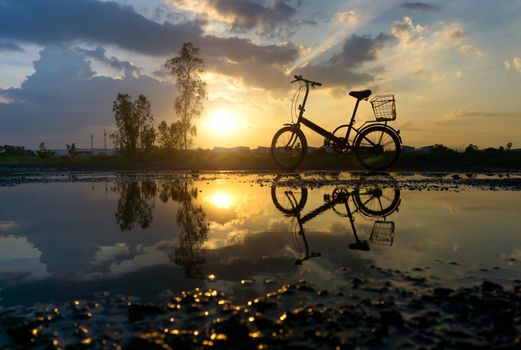 Reflection of Silhouette bicycle park on the waterfront. At sunset time in evening.