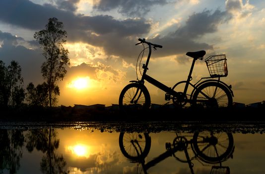 Reflection of Silhouette bicycle park on the waterfront. At sunset time in evening.