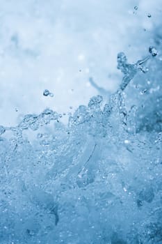 Blue water splash background from nature waterfall in rainforest. Portrait position.