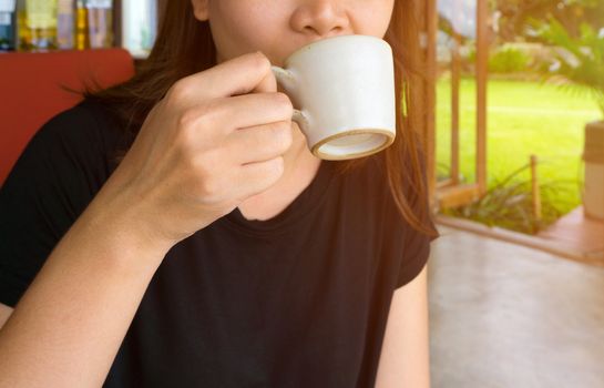 Close-up of female hand holding a cup of coffee and drinking coffee.
