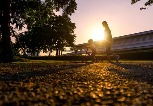 Asian mother help his son ride a bicycle.