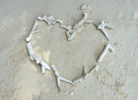 White broken dead coral in heart shape on the beach.