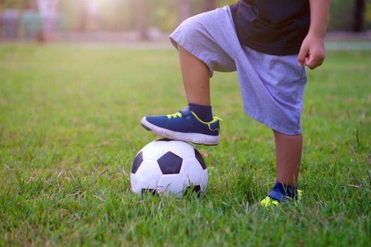 Asian kid playing soccer or football in the park. Step on the ball.