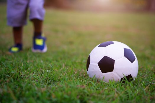 Asian kid playing soccer or football in the park. 