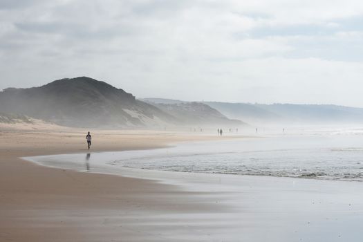 Active people on stretch of beach on a cloudy overcast summer day, Mossel Bay, South Africa