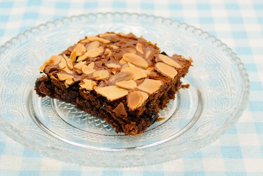 Chocolate brownie with almond topping on glass plated
