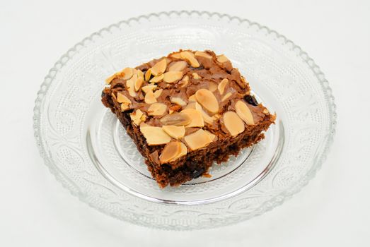 Chocolate brownie with almond topping on glass plated
