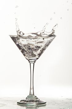 Glass, crystals of ice and pouring water on isolated studio background