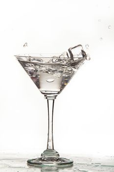 Glass, crystals of ice and pouring water on isolated studio background