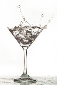 Glass, crystals of ice and pouring water on isolated studio background