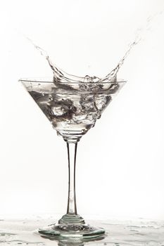 Glass, crystals of ice and pouring water on isolated studio background