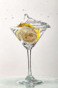 Glass of water, lemon and watersplashes on a black studio background