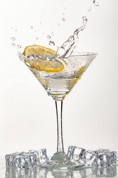 Glass of water, lemon and watersplashes on a black studio background