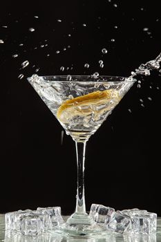 Glass of water, lemon and watersplashes on a black studio background