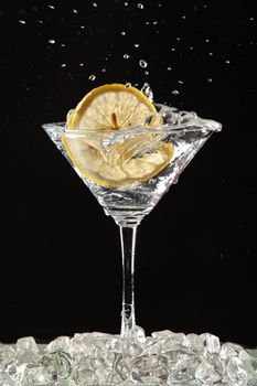 Glass of water, lemon and watersplashes on a black studio background