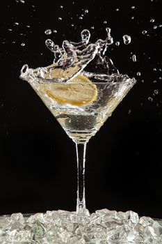 Glass of water, lemon and watersplashes on a black studio background