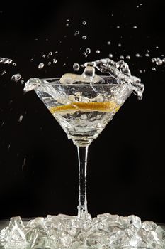 Glass of water, lemon and watersplashes on a black studio background
