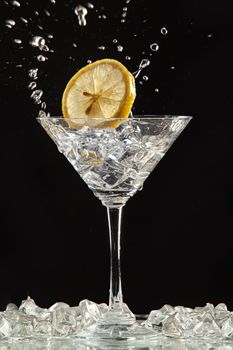 Glass of water, lemon and watersplashes on a black studio background