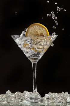 Glass of water, lemon and watersplashes on a black studio background