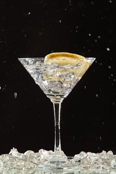 Glass of water, lemon and watersplashes on a black studio background