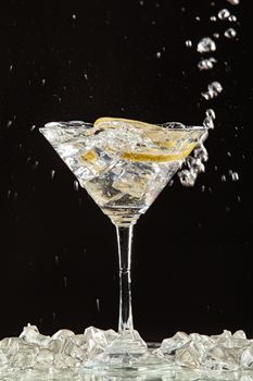 Glass of water, lemon and watersplashes on a black studio background