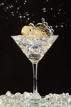 Glass of water, lemon and watersplashes on a black studio background