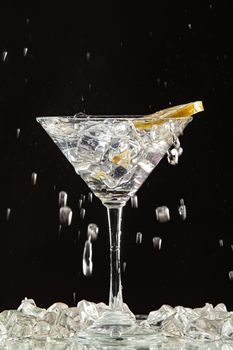 Glass of water, lemon and watersplashes on a black studio background
