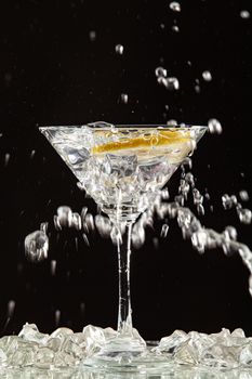 Glass of water, lemon and watersplashes on a black studio background