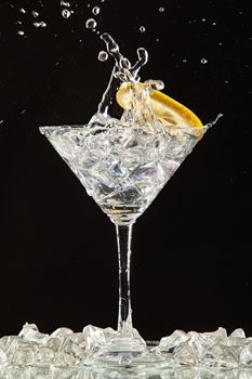 Glass of water, lemon and watersplashes on a black studio background